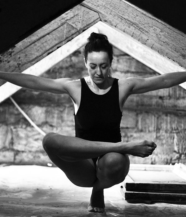 Woman in a graceful yoga pose against a dark background with mint light.